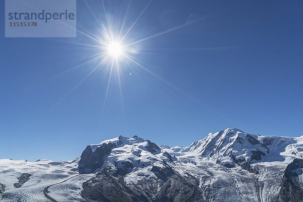 Schnee auf felsiger Landschaft unter sonnigem blauem Himmel