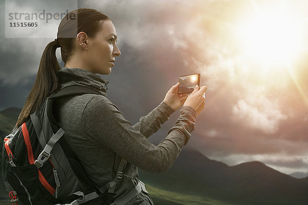 Kaukasische Frau fotografiert Berglandschaft mit Mobiltelefon