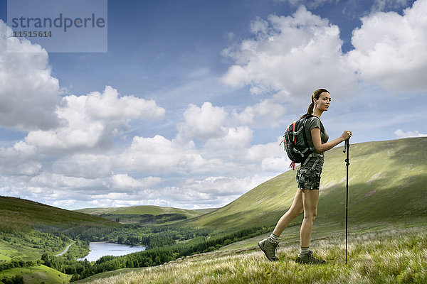 Kaukasische Frau beim Wandern auf einem grünen Hügel