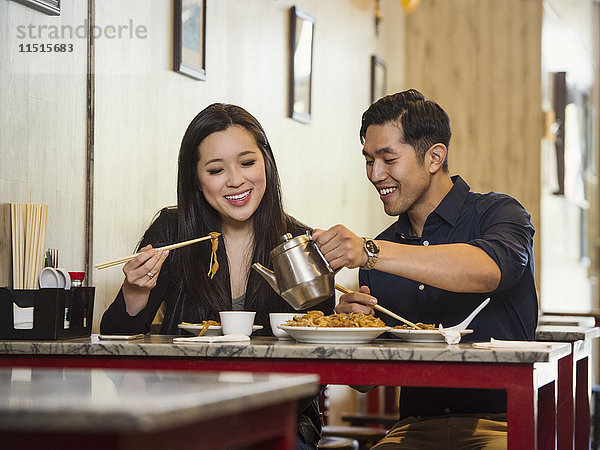 Chinesischer Mann schenkt einer Frau im Restaurant Tee ein