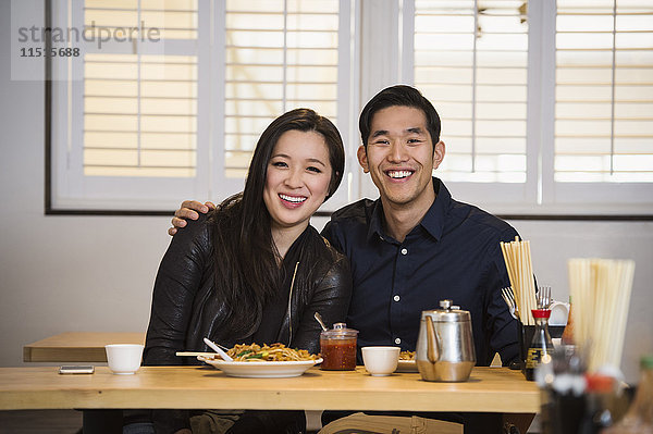 Lächelndes chinesisches Paar  das sich im Restaurant umarmt