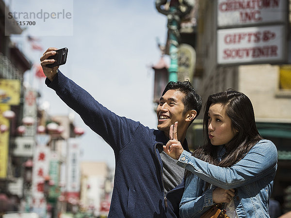 Lächelndes chinesisches Paar posiert für Handy-Selfie in der Stadt