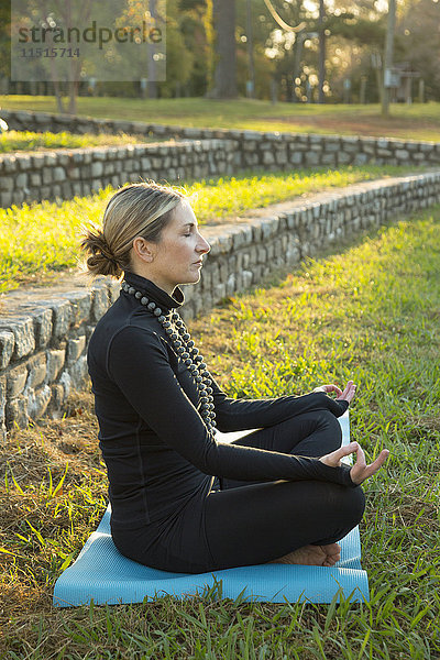 Kaukasische Frau meditiert im Park