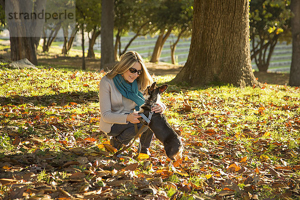 Kaukasische Frau streichelt Hund im Park