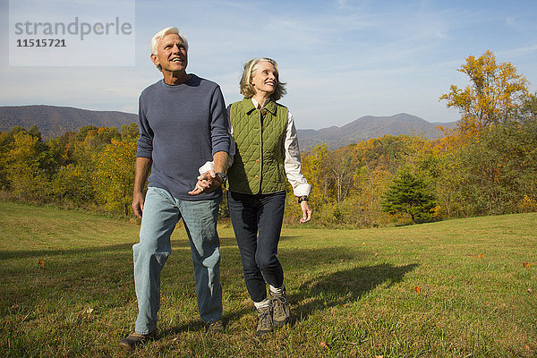 Älteres kaukasisches Paar geht in einem Feld spazieren