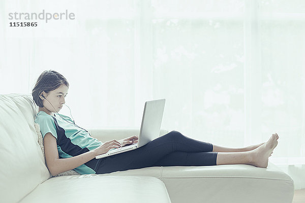 Mixed Race Mädchen auf Sofa mit Laptop