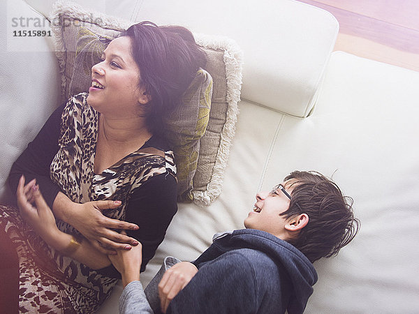 Mutter und Sohn liegen auf dem Sofa und lachen