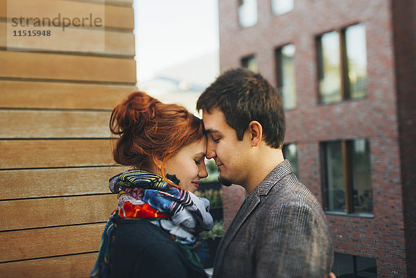 Kaukasisches Paar  das sich von Angesicht zu Angesicht in der Stadt umarmt