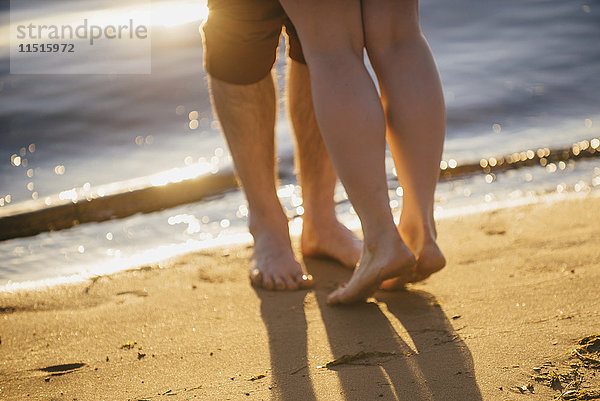 Beine eines Paares  das sich am Strand umarmt