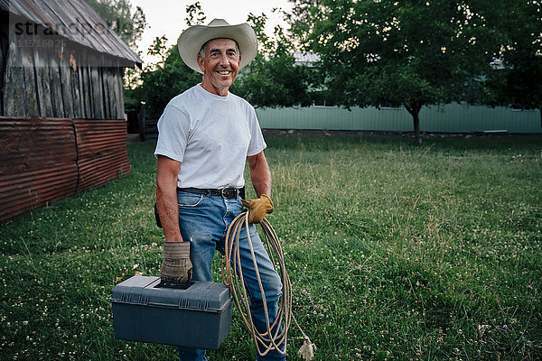 Kaukasischer Bauer trägt Seil und Werkzeugkasten