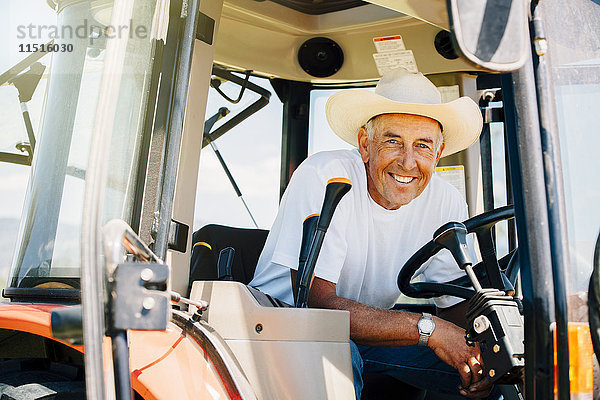 Porträt eines lächelnden kaukasischen Landwirts mit Traktor