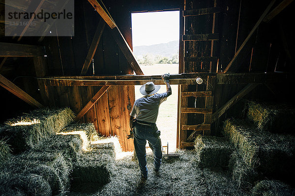 Kaukasischer Bauer ruht sich in einer Scheune neben Heuballen aus