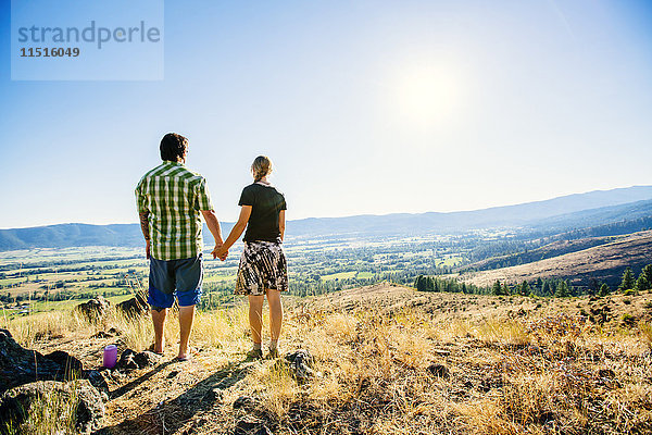 Kaukasisches Paar steht auf einem Hügel und hält Hände