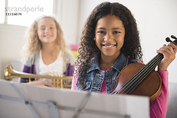 Lächelnde Mädchen posieren mit Geige und Trompete