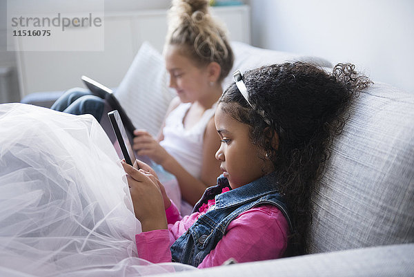 Mädchen benutzen digitale Tablets auf dem Sofa