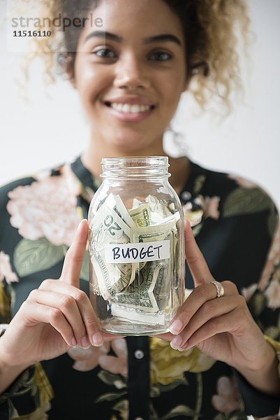 Mixed Race Frau hält Glas mit Budget Geld