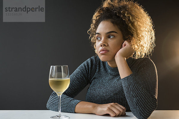 Gelangweilte gemischtrassige Frau mit Pullover  die Wein trinkt