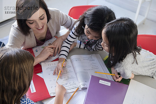 Lehrerin hilft Mädchen mit dem Arbeitsbuch im Klassenzimmer