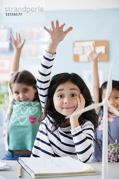 Mädchen lernen über Windmühlen und heben die Hände im Klassenzimmer