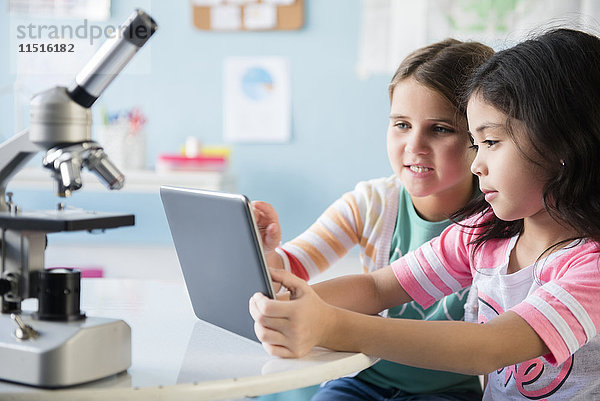 Kaukasische Mädchen teilen sich ein digitales Tablet im Klassenzimmer