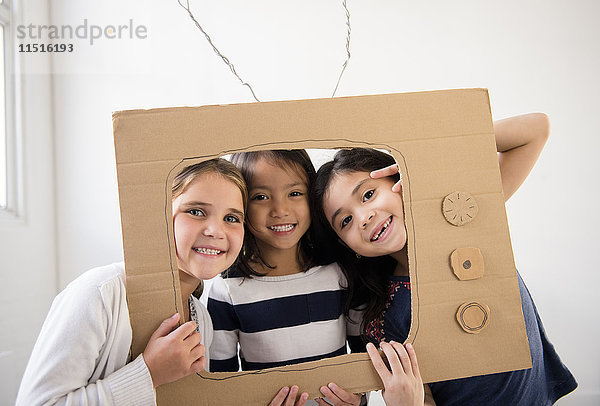 Porträt von lächelnden Mädchen  die einen Fernseher aus Pappe halten