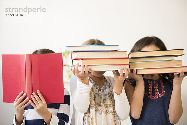 Mädchen halten sich Bücher vor das Gesicht