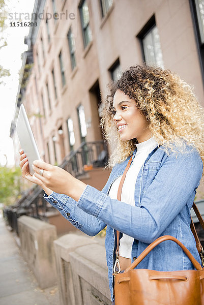 Gemischtrassige Frau in der Stadt posiert für ein Selfie mit digitalem Tablet