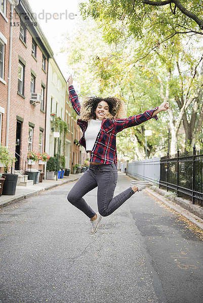 Gemischtrassige Frau springt vor Freude in der Stadt