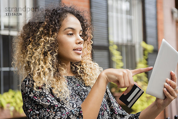 Mixed-Race-Frau beim Online-Shopping mit digitalem Tablet in der Stadt