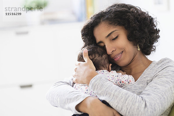 Hispanische Mutter  die ihre kleine Tochter umarmt