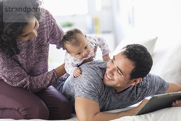 Hispanische Mutter hält ihre kleine Tochter auf dem Rücken des Vaters