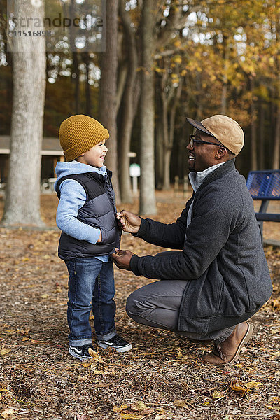 Vater zieht Weste für Sohn im Park zu