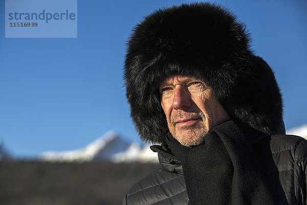 Kaukasischer Mann mit Schal und Pelzmütze im Winter