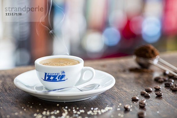 Eine Tasse mit Espresso  Zucker  Kaffeebohnen und Kaffeepulver auf einem Holztisch