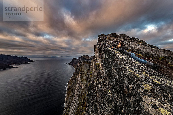 Frau schaut im Herbst vom Segla Peak auf der Insel Senja auf das Meer hinaus  Arktis Norwegen