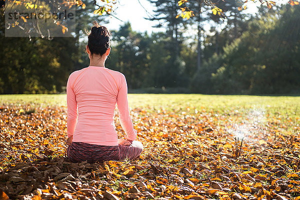 Frau macht am Herbsttag Yoga im Park