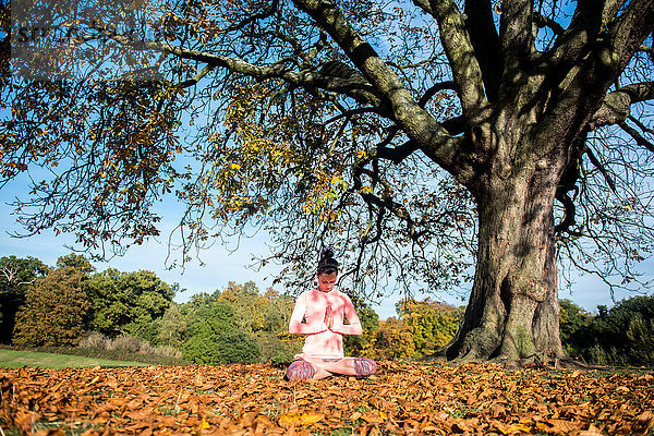 Frau macht am Herbsttag Yoga im Park