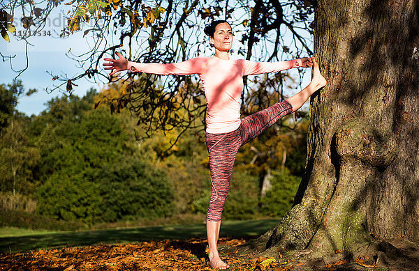 Frau macht am Herbsttag Yoga im Park