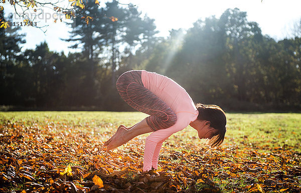 Frau macht am Herbsttag Yoga im Park