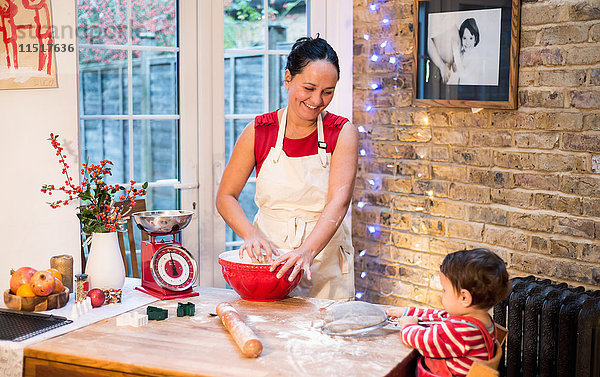 Mutter backt Weihnachtsplätzchen und lächelt den kleinen Jungen an