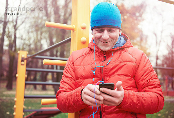 Älterer Mann  im Freien  mit Smartphone  mit Kopfhörern