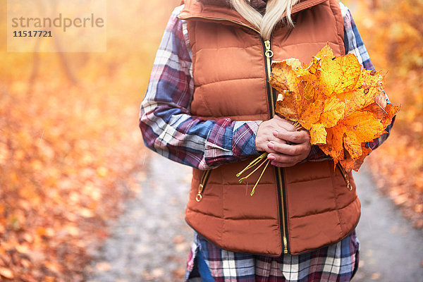 Frau im Freien stehend  Herbstblätter haltend  Mittelteil