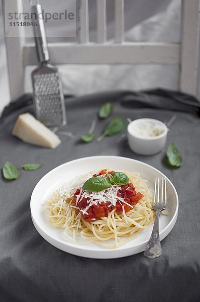 Spaghetti mit Tomatensauce  garniert mit geriebenem Parmesan und frischen Basilikumblättern