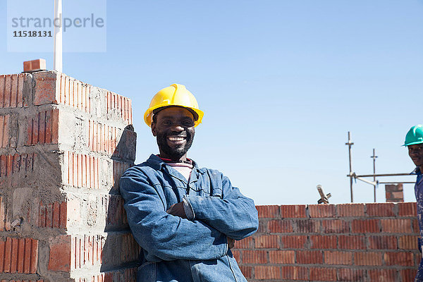 Porträt eines Bauunternehmers mit Schutzhelm  der lächelnd in die Kamera schaut