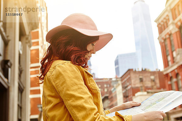 Junge Touristin mit langen roten Haaren betrachtet Karte auf Straße  Manhattan  New York  USA