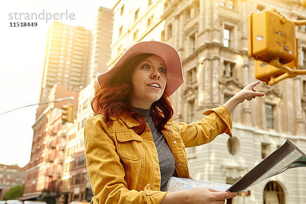 Junge Touristin mit langen roten Haaren  die auf der Straße ein Taxi anhält  Manhattan  New York  USA