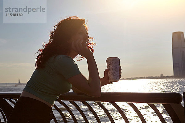 Junge Touristin lehnt mit Kaffee am Ufergeländer  Manhattan  New York  USA