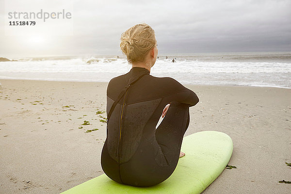 Surferin sitzt auf einem Surfbrett und blickt vom Rockaway Beach  New York  USA