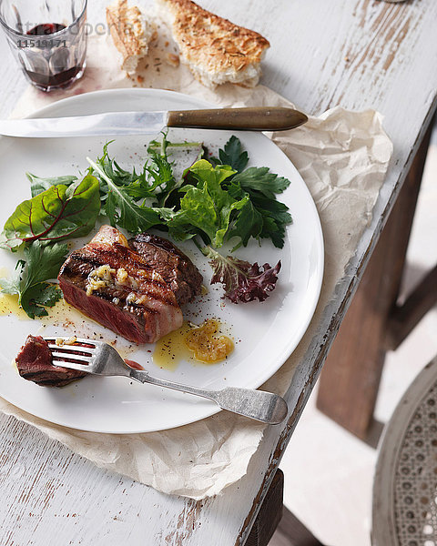 Filet Mignon mit Knoblauchbutter  gemischtem Blattsalat  Rotwein und Krustenbrot auf Teller im Restaurant  Nahaufnahme