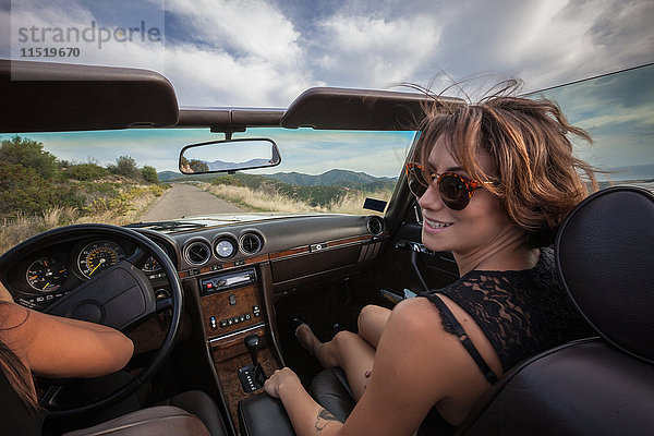 Zwei junge Frauen in einem Cabriolet  Fahrt auf einer Panoramastraße  Rückansicht